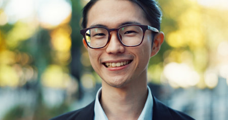 Man, Asian in city and face with travel or commute to work, glasses and professional in Tokyo. Corporate lawyer in urban street, journey to office and happiness in portrait with business visionの写真素材