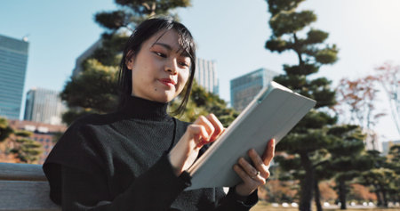 Happy asian woman, tablet and research at park in city for social media or outdoor networking....