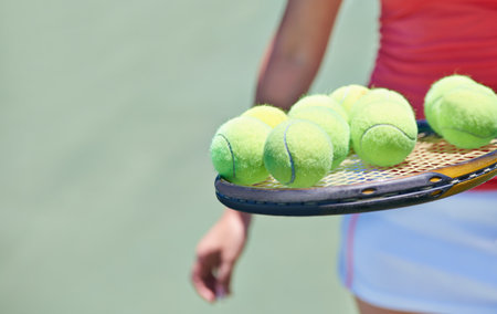 Woman, tennis player and balls on racket for outdoor game, match or competition on court. Closeup or hands of female person or athlete in sports with bat and equipment for training on mockup spaceの写真素材