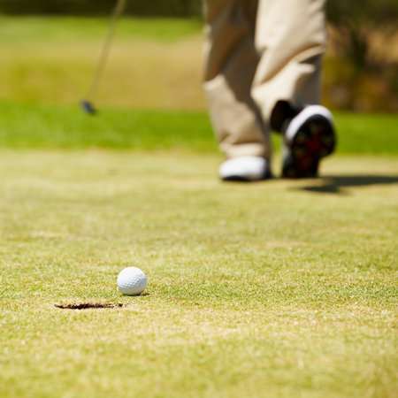 Golf, ball and hole on a green in summer for sports, recreation or leisure closeup for hobby. Grass, ground or field with a golfer walking on a course during a game of competition or trainingの写真素材