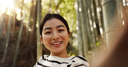Japanese woman, portrait and selfie in forest with smile, pride and bamboo in bush for post on web...
