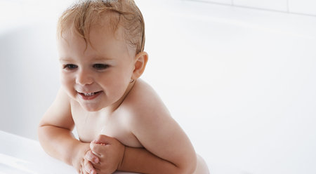 Face of baby in bath, clean smile or mockup in morning routine for health, wellness or body care in...