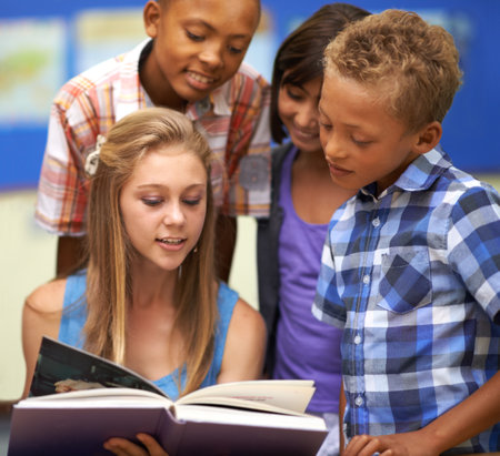 Children, reading book and classroom education for teaching, learning and support in language development. Happy kids with mentor or girl in leadership helping students with education or storytellingの写真素材