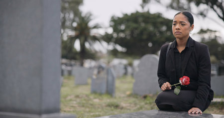 Sad woman, graveyard and rose on tombstone in mourning, loss or grief at funeral or cemetery. Female person with flower in depression, death or goodbye at memorial or burial service for loved oneの写真素材