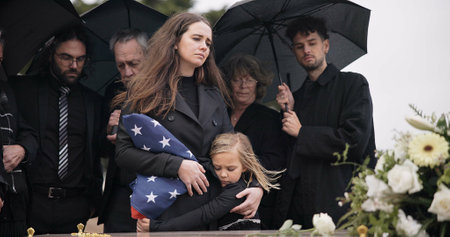 Funeral, family and sad people with American flag, grief and mourning death, burial and widow depressed at farewell event. Kid, mother and group gathering at coffin, casket and crying at ceremonyの写真素材