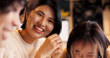 Japanese friends, laughing and talking in restaurant for dinner, vacation and hungry to order healthy food. Women, man or happy together on lunch in tokyo city or funny joke by bonding in coffee shopの写真素材