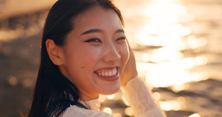 Japanese, woman and face, ocean and sunset with travel, tourism and happiness in nature....