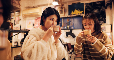 Japanese friends, cheers and coffee in restaurant for dinner, vacation and hot drinks to celebrate on holiday. Women, man and happy together at supper in tokyo city and cappucino by bonding in cafeの写真素材