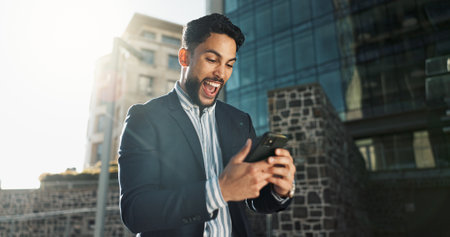 Phone, dance and a businessman in the city for celebration of success, bonus or promotion. Wow, mobile and winner with a young employee cheering for goals, target or corporate achievement in townの写真素材