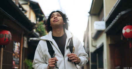 Man, Japan and travel or explore city with backpack for adventure, vacation or cultural history. Asian person, walk and street or urban buildings for education as tourist for holiday, weekend or tripの写真素材