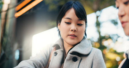 Businesswomen, japan and talking by office buildings in city, collaboration and discussion in corporate career. Manager, employee and communication in professional job in tokyo and project feedbackの写真素材