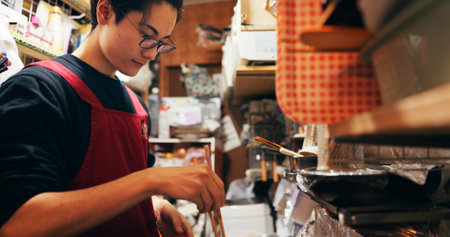 Japanese chef man, cooking and chopsticks by stove, service or catering job on heat, flame or ready. Person, restaurant or cafeteria in kitchen for meal prep, working or thinking for recipe in Tokyoの写真素材