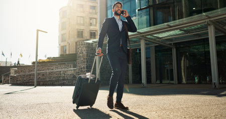 Business man, suitcase and phone call in city for professional communication, transport and travel news or information. Happy corporate worker with mobile chat, luggage and walking outdoor to airportの写真素材
