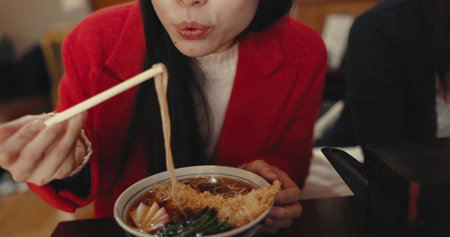 Woman, mouth and blowing ramen noodles in restaurant for dinner, diet and meal in cafeteria. Closeup, hungry lady and chopsticks for eating hot spaghetti, Japanese cuisine or lunch in fast food dinerの写真素材