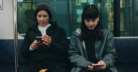 Women, travel and train with friends, smartphone and relax with digital app, online chatting and social media. Search internet, transportation and people with cellphone, website information or typingの写真素材