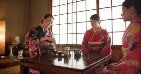 Japanese, women and matcha for tea ceremony in Chashitsu with kimono dress and traditional custom. People, temae and vintage style outfit for culture, fashion and honor with antique crockeryの写真素材
