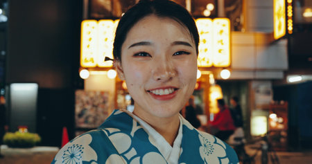 Japanese woman, kimono or happy in portrait at night, city or religion on heritage celebration. Young person, face or traditional clothes in tokyo in beauty, wellness or pride in indigenous fashionの写真素材