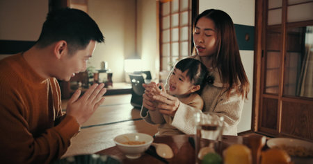 Family, nutrition and dinner with girl, parents and Japanese with joy, meal and home with happiness. Mother, apartment and father with kid, food and bonding together with supper, smile and loveの写真素材