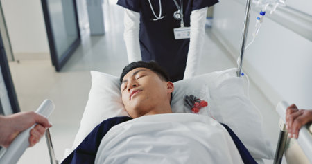 Asian man, patient and push bed in hospital for surgery, emergency or medical problem in corridor. Medicine, professional or person with stretcher for wellness, service and risk in clinic or jobの写真素材