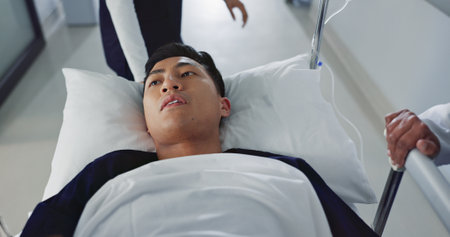 Emergency, bed and man rush in hospital for medical surgery with team of doctors in clinic corridor for healthcare. Sick, group and person in first aid for accident health service or assessmentの写真素材