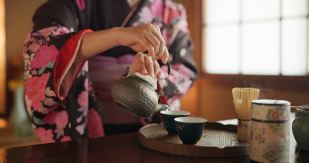 Japanese, hands and matcha for tea ceremony in Chashitsu room with kimono dress and traditional custom. Person, temae and vintage style outfit for culture, fashion and honor with antique crockeryの写真素材