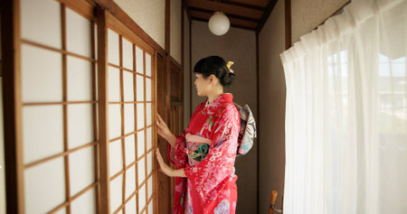 Japan, woman and kimono in corridor for tradition, tea ceremony and hallway of Chashitsu room or door. Entrance, person and vintage dress or fashion for temae, ritual and waiting for hospitalityの写真素材