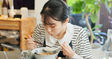 Restaurant, food and Japanese woman with noodles for eating meal, lunch and dinner in cafe. Ramen, cafeteria supper and person with chopsticks for traditional cuisine for health, wellness and hungerの写真素材
