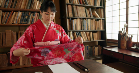 Woman, art and Japanese painting tool in a living room with traditional culture, home and dress. Zen, Tokyo and calm with indigenous ritual, drawing and paper for creativity with document and silkの写真素材