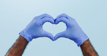 Man, doctor and heart hands with gloves for healthcare isolated against a blue studio background....