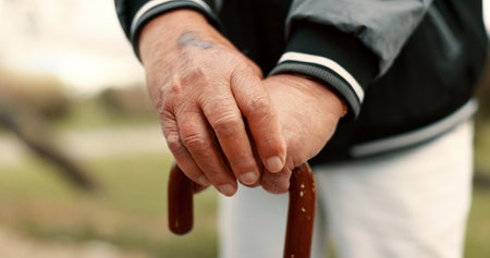 Hands, cane and elderly man in nature for walking for fresh air, exercise or peace in a park. Environment, closeup and senior male person in retirement with a stick for support in outdoor garden.の写真素材