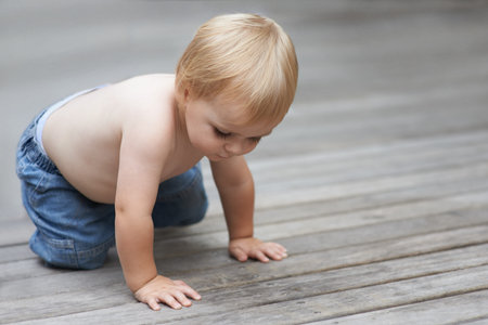 Toddler, playing on floor outdoor for development with relax, curiosity and early childhood in...