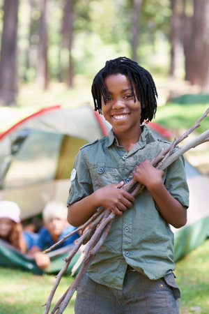 Wood, camping or portrait of African boy in nature playing, adventure or holiday vacation in park. Relax, collect or happy kid with smile or sticks in woods, garden or forest for hiking or wellnessの写真素材