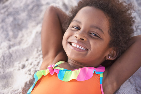 Happy, child and portrait on beach sand for childhood and summer holiday with sunshine in nature. Black girl, young and smile face to relax on vacation, cape town and seaside for wellness in outdoorの写真素材