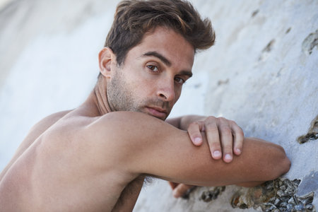 Man, serious and fitness body with arms, muscle and wellness outdoor by a wall. Summer, thinking and idea of a male person from Brazil with strong, relax and topless with confidence and calmの写真素材