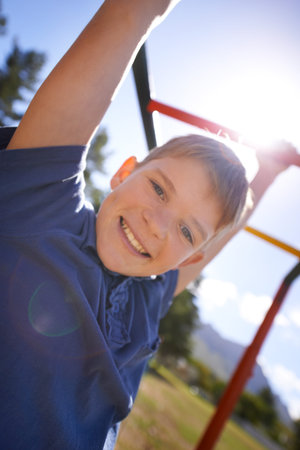 Child, monkey bars and smile in portrait, hanging game and obstacle course on outdoor adventure at...
