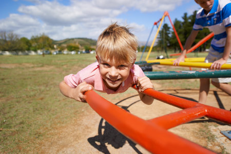 Child, boy and fun on playground in portrait, smile and outdoor adventure on merry go round at park....