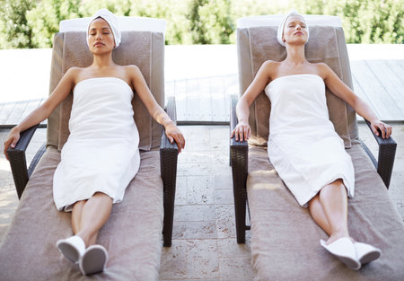 Women, spa and sleeping outdoor after massage, facial or hotel beauty treatment with rest. Relax, friends and nap from physical therapy, care and hospitality from skincare and wellness with peaceの写真素材