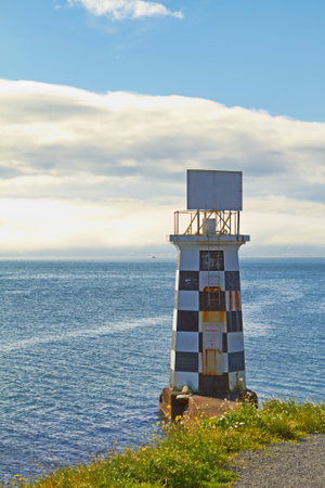 Lighthouse, ocean and blue sky by beach in nature for holiday, vacation or travel destination. Water, clouds and signal tower by sea for outdoor summer weekend trip on tropical island in cape town.の写真素材