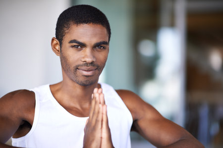 Man, portrait and meditation in home for fitness, wellness or diet on blurred background for exercise and namaste. African person and trainer with smile and hands together for zen, calm and peaceの写真素材