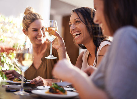 Friends, wine and women laughing at restaurant with drinking, bonding and relax outdoor in city for celebration. People, face and happy with alcohol at cafe for social gathering, funny gossip or jokeの写真素材