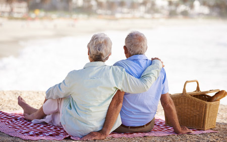 Elderly, couple and relax beach for picnic together for summer bonding or travel connection, outdoor or view. Old woman, man and back for vacation holiday at ocean in Hawaii for rest, peace or funの写真素材