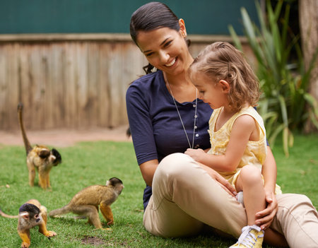Animal, mother and young girl with monkey for wildlife rescue, outdoor activity or interactive experience in nature. Conservation, zoo and happy family for bonding, holiday and travel at sanctuaryの写真素材