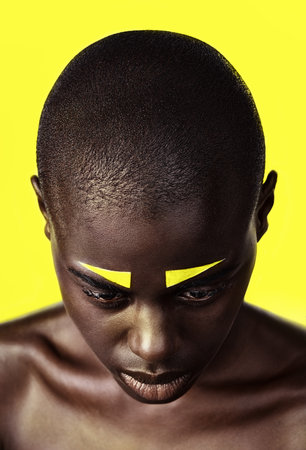 Black woman, makeup and cosmetics with beauty, skin and creative with studio and color. Model, closeup and face paint for artistic, contrast and aesthetic for glamour isolated on yellow backgroundの写真素材