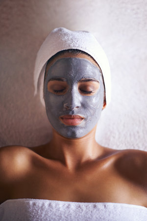 Woman, top view with face mask and beauty with skincare, charcoal for treatment and dermatology at day spa. Peace, calm and detox for skin, healthy with wellness and cosmetics for facial ad self careの写真素材