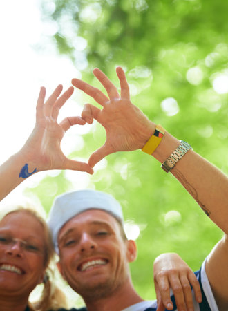 Portrait, festival and couple with heart sign, love and happiness with romance gesture and celebration. Face, people and outdoor with man and woman with symbol for love and marriage with joyの写真素材