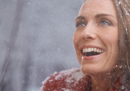 Happy, excited and face of woman with snow outdoors for season, snowing weather and cold climate. Travel, fashion and person smile in nature on winter holiday, vacation and weekend in Switzerlandの写真素材