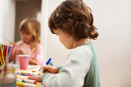 Child, writing and drawing with colorful art at home for learning, education or creativity. Young boy with color pencil for sketching, activity or artwork in early childhood development at the houseの写真素材