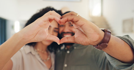 Man, woman and portrait with heart hands for valentines day with smile, care and marriage in home. Happy couple, celebration and emoji for love, romance and commitment to relationship in apartment.の写真素材
