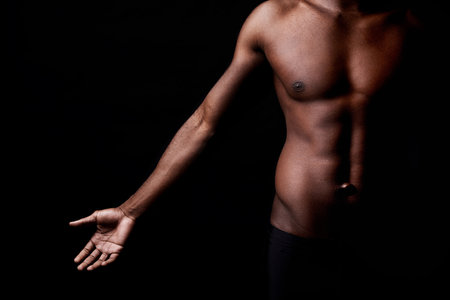 Black man, body, and muscle with fitness in shadow for exercise or workout on a dark studio background. Closeup of young African male person or bodybuilder with masculine or muscular figure on mockupの写真素材