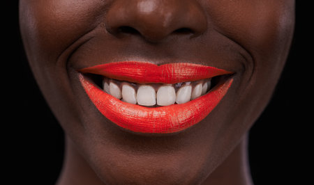 Black woman, lipstick and smile for beauty, cosmetics and bright makeup color on dark background. Bold, vibrant and orange lip balm with happy model, cosmetology and teeth for glamour in studioの写真素材